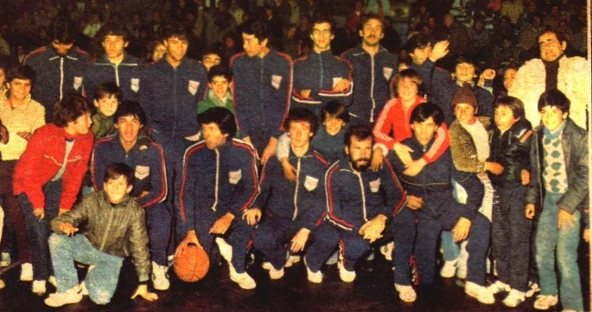 El plantel campeón con camperas de la selección de Soriano, rodeado de chicos, en el gimnasio